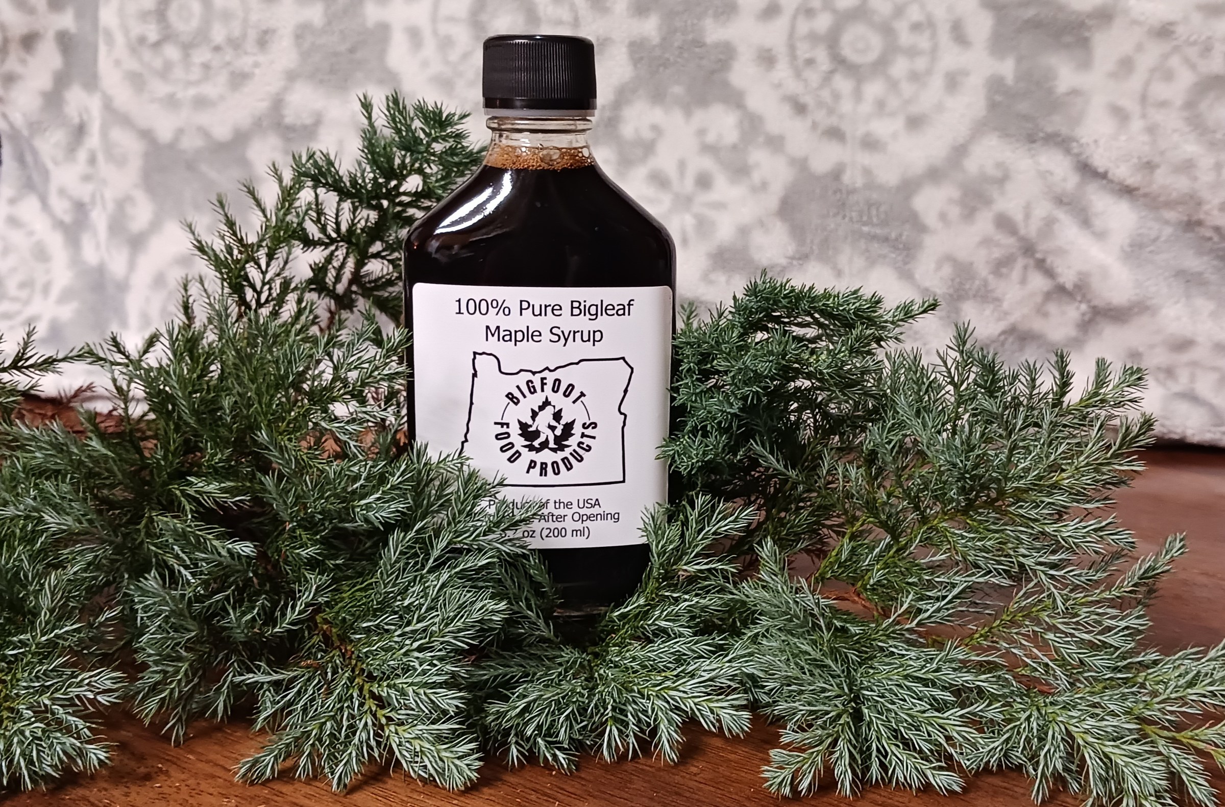 Bottle of Bigfoot bigleaf maple syrup with evergreen boughs
