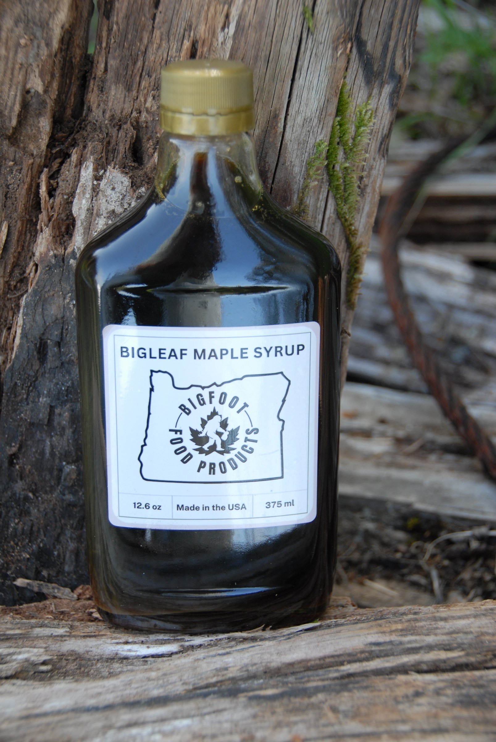 Bottle of Bigfoot bigleaf maple syrup on weathered wood