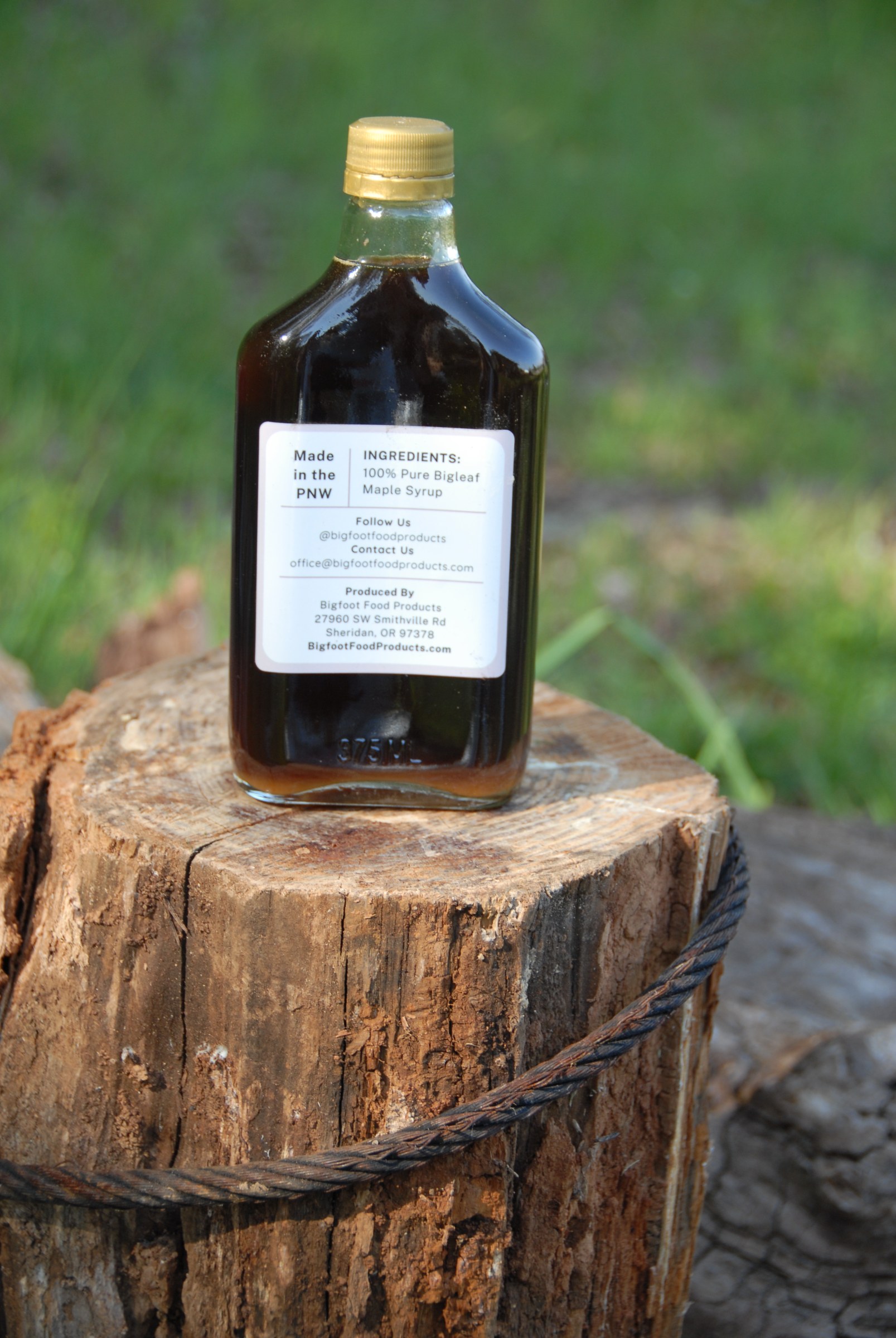 Bottle of bigleaf maple syrup on a fence post in the pasture